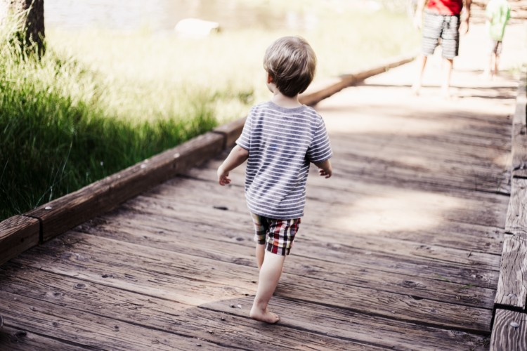 Lapsi kävelee pitkospuilla kesäsäässä.