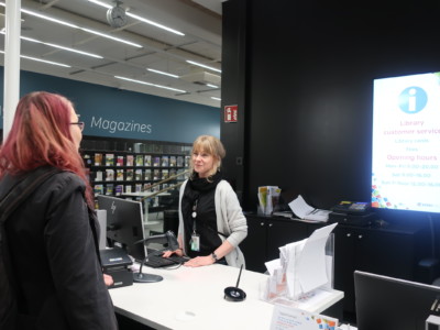 Anniina Ala-Soini kysyy neuvoa kirjaston infotiskin työntekijältä.