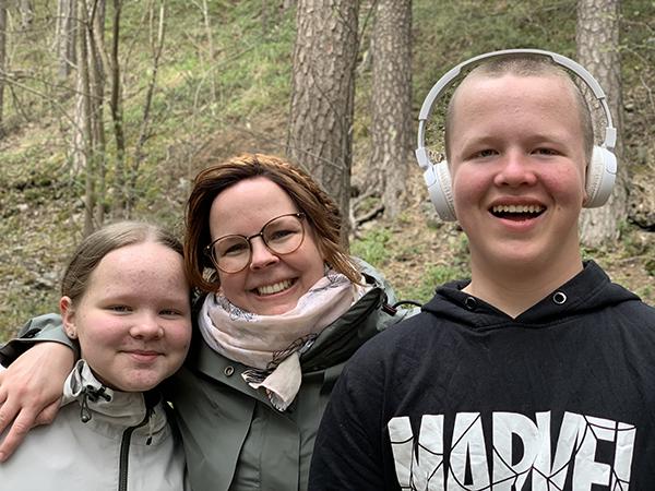 Elsi, Hanna-Leena ja Rasmus hymyilevät metsässä.