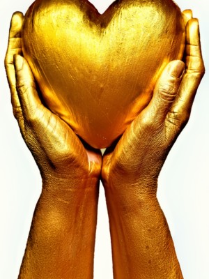 Kullanväriset ylös nostetut kädet pitävät välissään kullanväristä sydäntä.