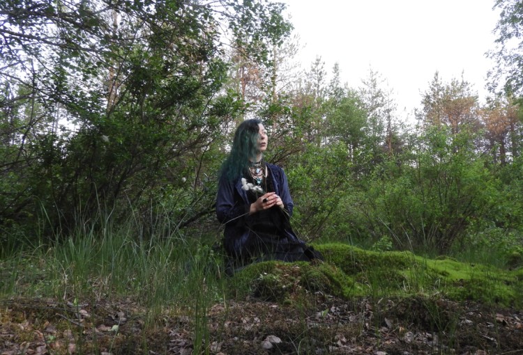 Essi Palojärvi istuu metsikössä.