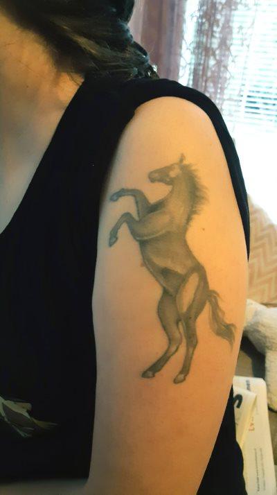 Olkavarsi, jossa tatuointi hevosesta takajaloillaan.
