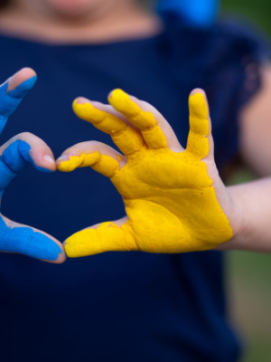Ukrainan lipun väreillä maalatut kämmenet, jossa sormet muodostavat sydämen.