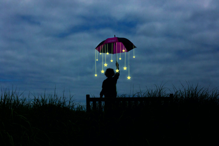 Ihmishahmo pimeässä pitää kädessä sateenvarjoa, josta roikkuvat tähdet.
