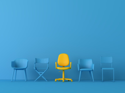 Keltainen tuoli sinisessä huoneessa sinisten tuolien keskellä.