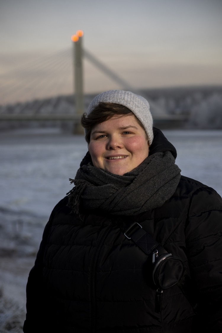 Paula Kivelä ulkona talvivaatteissa, taustalla Jätkänkynttilä-silta Rovaniemellä.