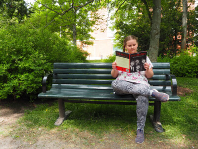 Aida istuu puistonpenkin oikealla reunalla ja lukee Beatleksestä kertovaa lehteä.