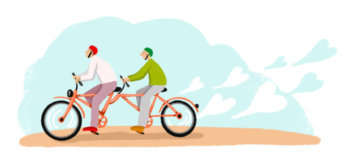 Kaksi ihmistä ajavat tandem-polkupyörällä, jonka takapyörästä leijuu ilmaan sydämiä.
