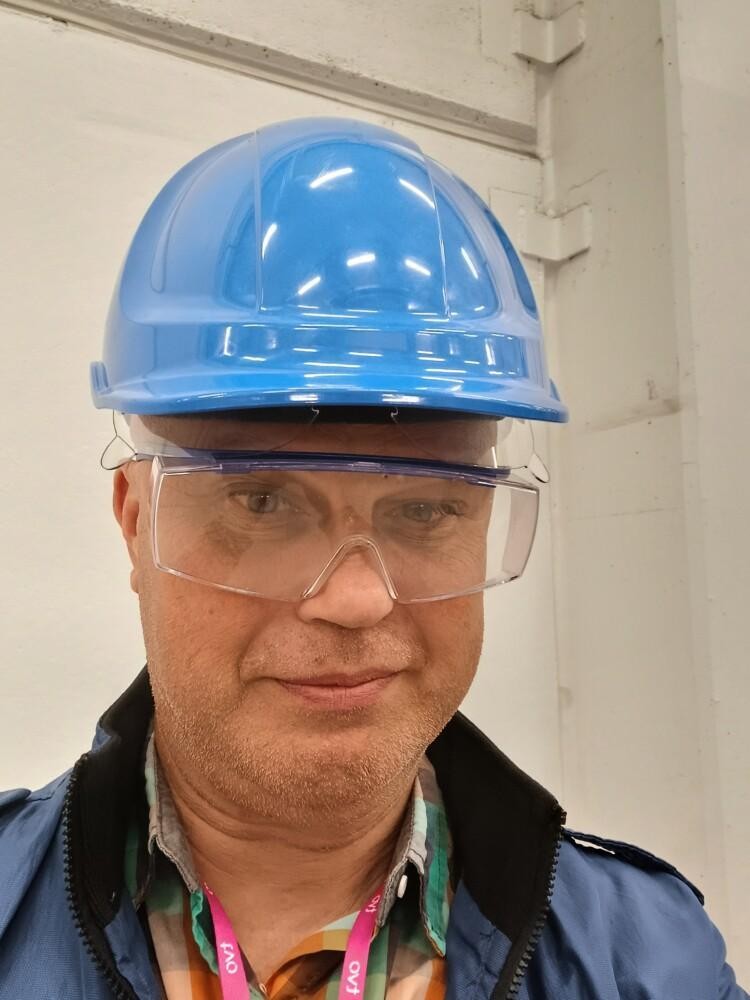 Lähikuva Petteri Kermisestä. Hänellä on päässään sininen rakennustyömaan kypärä ja suojalasit.