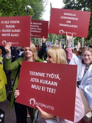 Autismiliiton työntekijöitä ja muita tukijoita kyltteineen mielenosoituksessa.