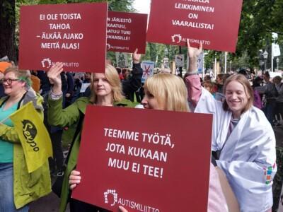 Autismiliiton työntekijöitä ja muita tukijoita kyltteineen mielenosoituksessa.