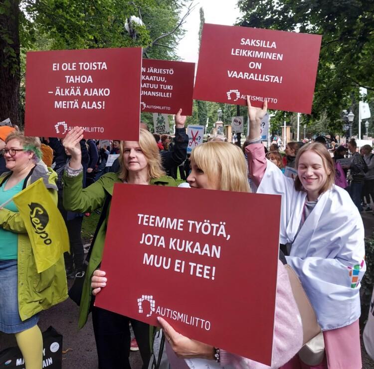 Autismiliiton työntekijöitä ja muita tukijoita kyltteineen mielenosoituksessa.