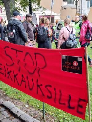 Ihmisiä mielenotoistuksessa. Punaisessa julisteessa lukee Stop leikkauksille.
