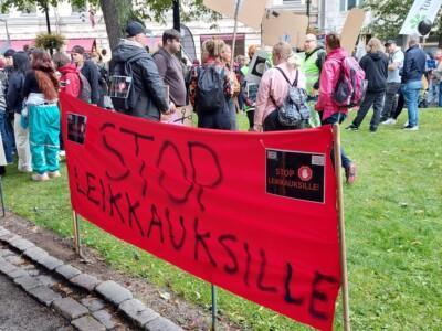 Ihmisiä mielenotoistuksessa. Punaisessa julisteessa lukee Stop leikkauksille.