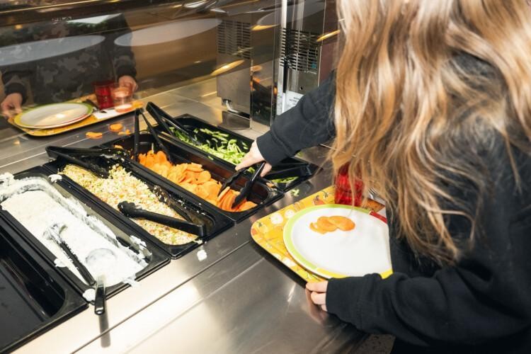 Lapset ottamassa salaattia ruokalan linjastolla.