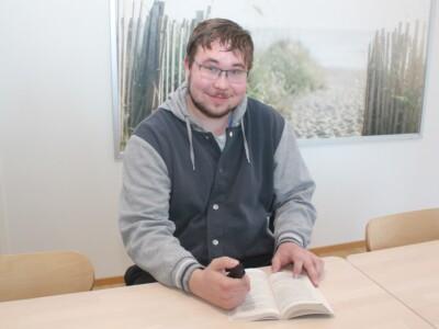 Veikko Pesonen lukee kirjaa lukukynän avulla.