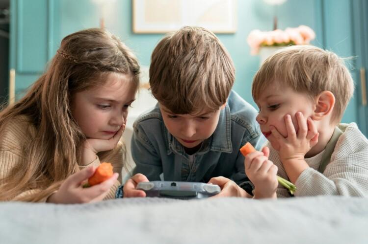Kolme lasta katsovat yhdessä kännykkää