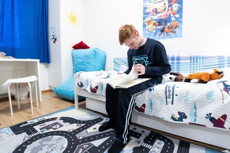 Nuori mies istuu sängyllä ja katsoo kirjaa.