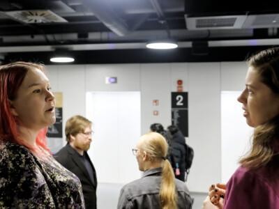 Neljä ihmistä keskustelemassa toistensa kanssa: kaksi naispuolista etualalla, kaksi miespuolista taka-alalla.