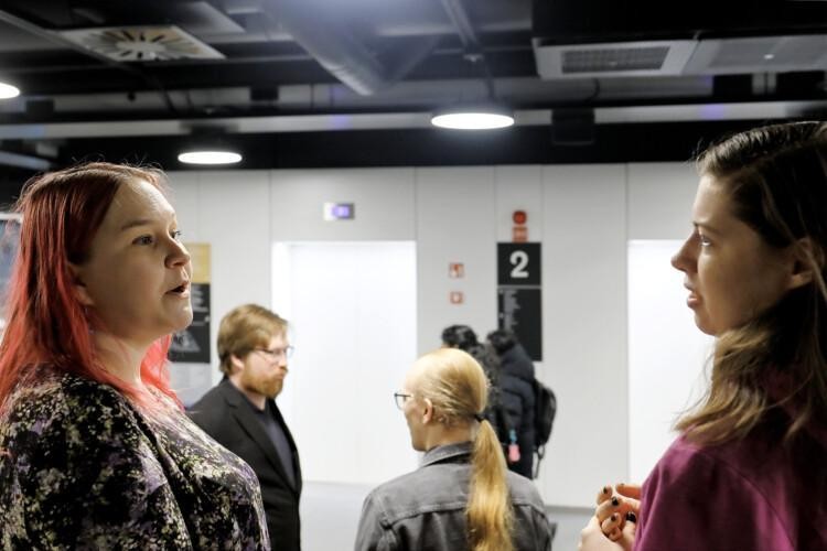 Neljä ihmistä keskustelemassa toistensa kanssa: kaksi naispuolista etualalla, kaksi miespuolista taka-alalla.