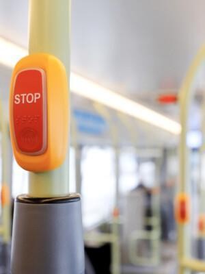 Bussin STOP-painike, taustalla tyhjä bussi.