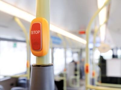Bussin STOP-painike, taustalla tyhjä bussi.