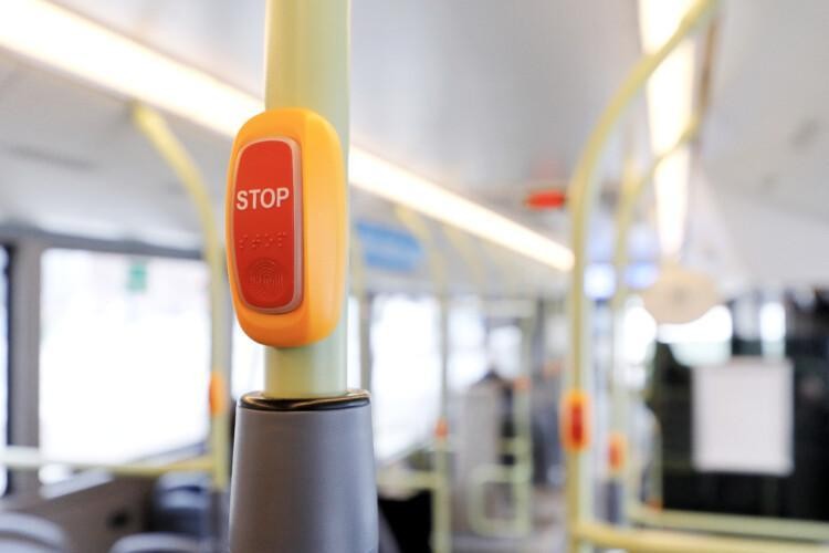 Bussin STOP-painike, taustalla tyhjä bussi.