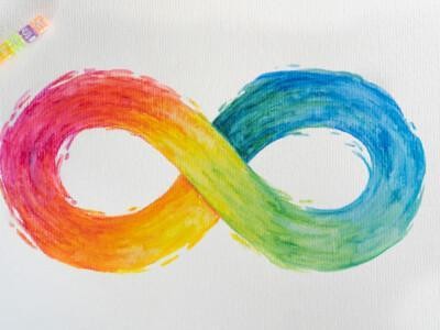 Neurokirjon äärettömyysmerkki sateenkaaren väreissä. Yläkulmassa pieni kirjaimin kirjoitettuna sana autism.