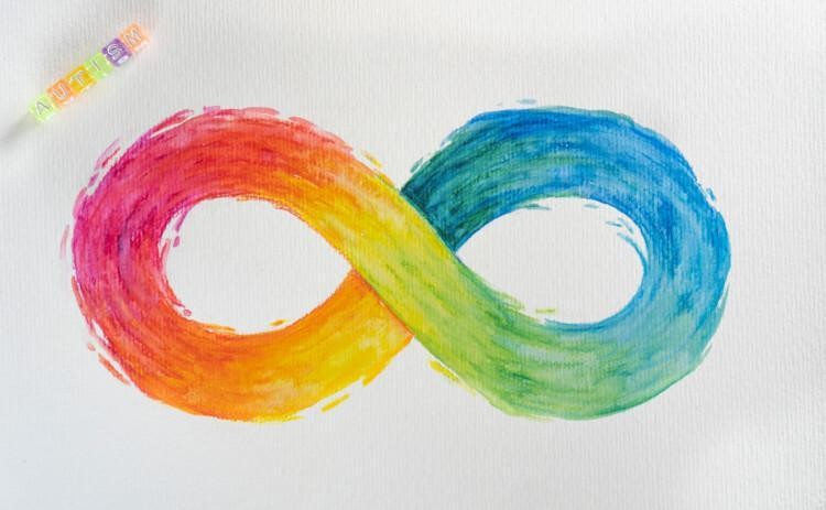 Neurokirjon äärettömyysmerkki sateenkaaren väreissä. Yläkulmassa pieni kirjaimin kirjoitettuna sana autism.